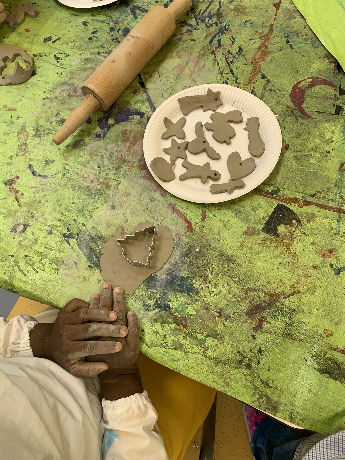 Kind formt aus Ton Figuren mit Ausstechformen, auf einem Teller liegen kleine Tonmotive. Kind formt aus Ton Figuren mit Ausstechformen, auf einem Teller liegen kleine Tonmotive.