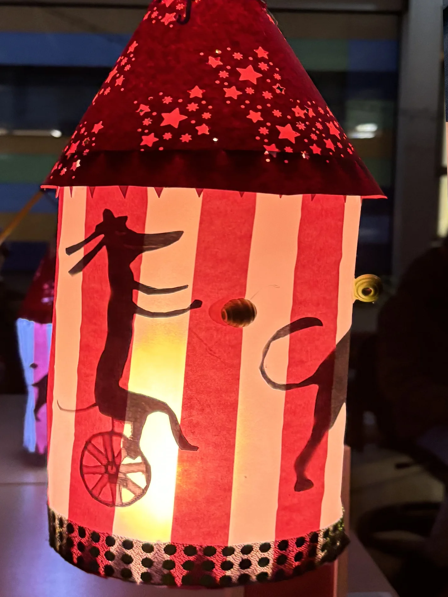 Selbstgebastelte Laterne mit rotem Dach und Zirkusmotiven leuchtet im Dunkeln. Selbstgebastelte Laterne mit rotem Dach und Zirkusmotiven leuchtet im Dunkeln.