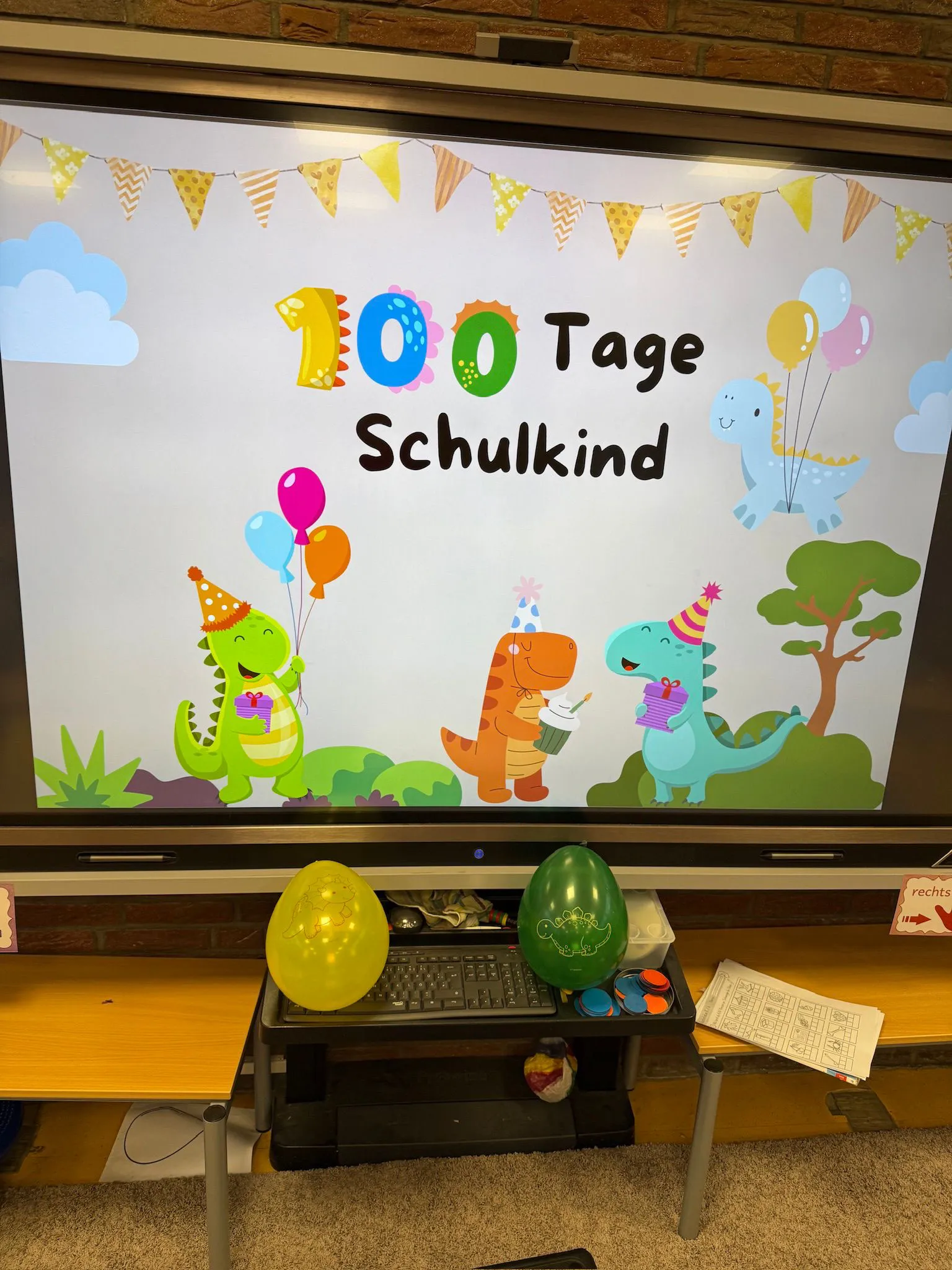 Digitale Tafel zeigt buntes Motiv‚ 100 Tage Schulkind‘ mit Luftballons und fröhlichen Dinosauriern. Digitale Tafel zeigt buntes Motiv‚ 100 Tage Schulkind‘ mit Luftballons und fröhlichen Dinosauriern.