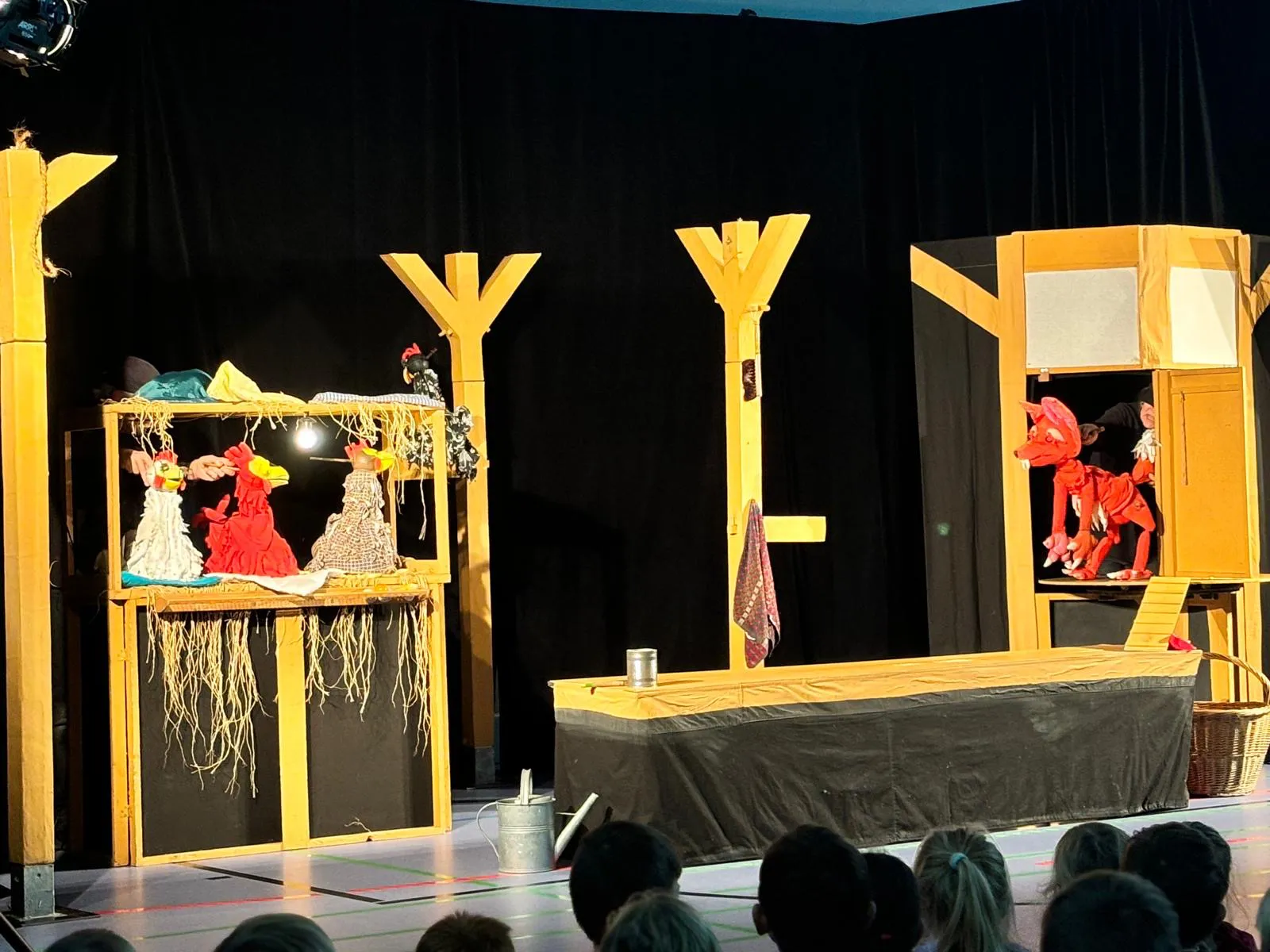 Figurentheater-Aufführung mit bunten Handpuppen auf einer Schulbühne, vor einem Publikum aus Kindern Figurentheater-Aufführung mit bunten Handpuppen auf einer Schulbühne, vor einem Publikum aus Kindern